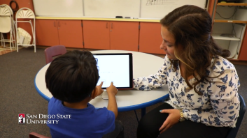 Member of Pruit Lab guiding a child in reading a story on a tablet